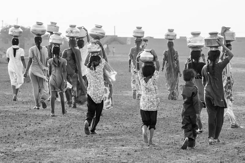 Human Right to Water in India - rural women and girls struggling through the scorching heat of Thar desert in Jaisalmer district, Rajasthan for procuring potfuls of water, due to failure of the promised piped water supply from Indira Gandhi Nahar Pariyojana bringing water from river Sutlej in Punjab